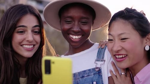 Friends Smiling at Cellphone in Urban Environment