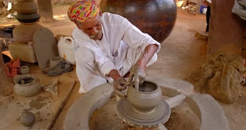 Potier professionnel lançant le tour du potier et façonnant un pot dans un atelier de poterie