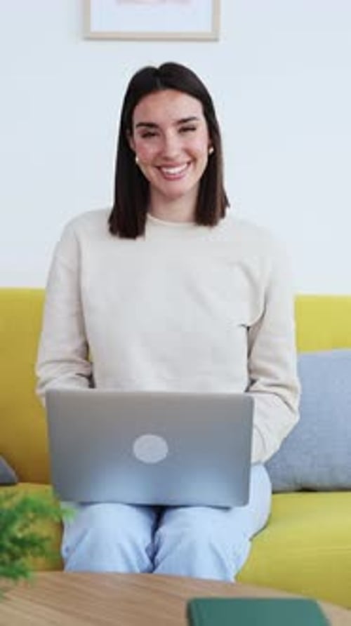 Woman Sits with Laptop on Couch Smiling