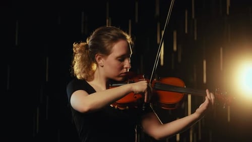 Woman Playing Violin With Golden Back Lighting