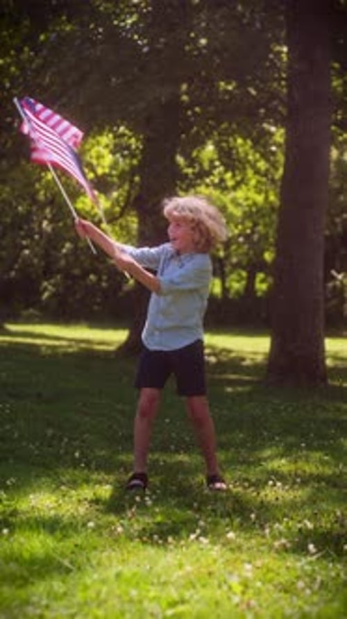 Enthusiastic Boy Waving American Flags in a Park