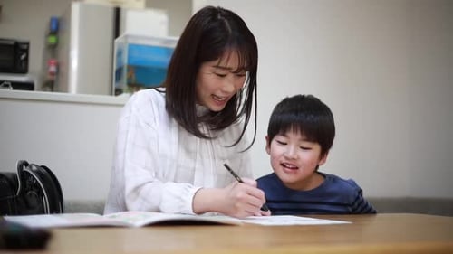 Woman Helps Child with Homework at Table