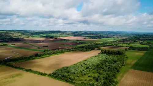 Aerial landscape forward shot of cloudy bright and shady view of agricultural areas hills and little