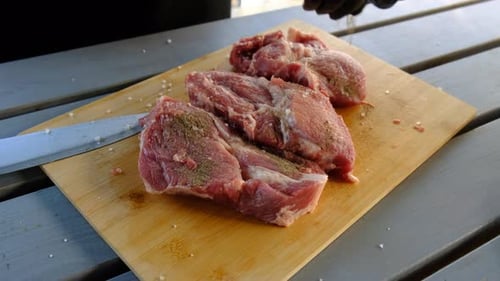 Gloved hands seasoning raw meat on cutting board
