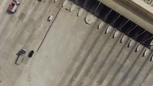 Uma vista aérea rotativa de uma praça de pedágio de uma rodovia da cidade, veículos pesados e outros entrando em um