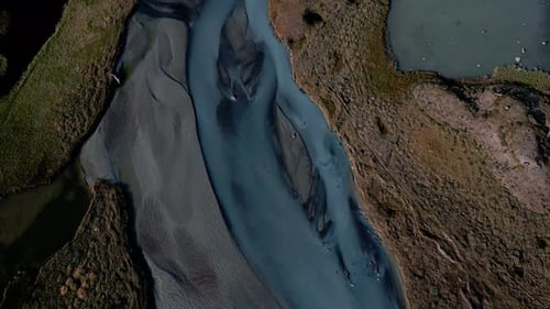 Breathtaking max view tracking shot of a river, that flows through a stony and barren landscape, sun