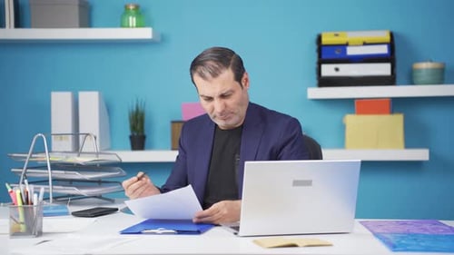 Stressed Businessman Reviews Paperwork in Office