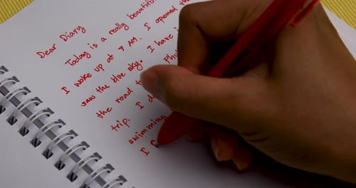Handwriting a Diary with a Red Pen Overhead Shot Close Up of Woman's Hand.