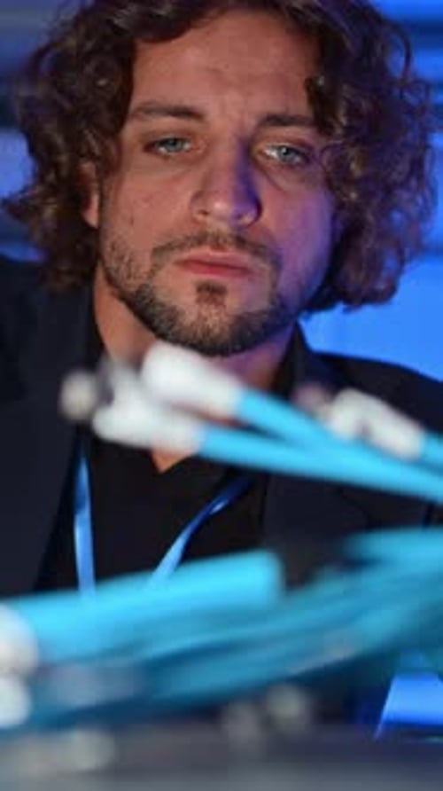 Man analysing cables in a data center. Vertical
