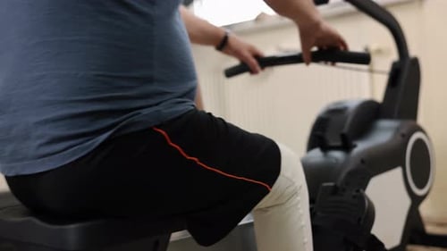 Man Exercises on a Rowing Machine Indoors