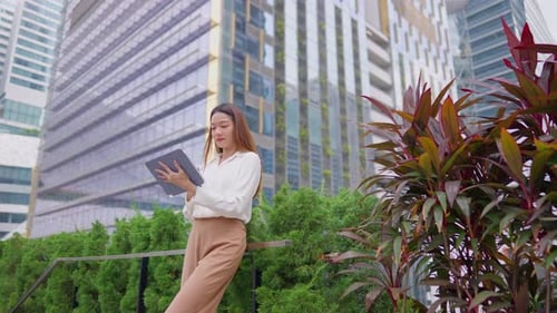 Asian young businesswoman using digital tablet while standing in the city.