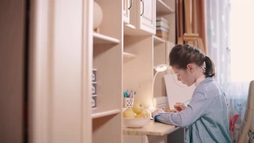Girl Drawing at Desk in Bright Room