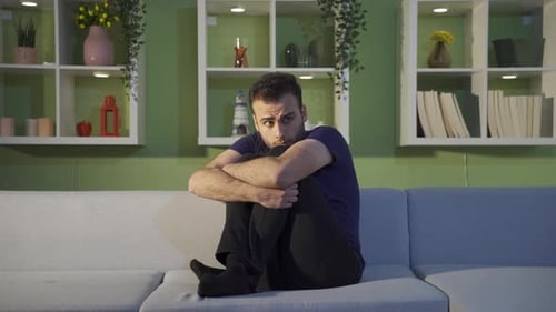 Sad Man Sitting on Couch in Interior Setting