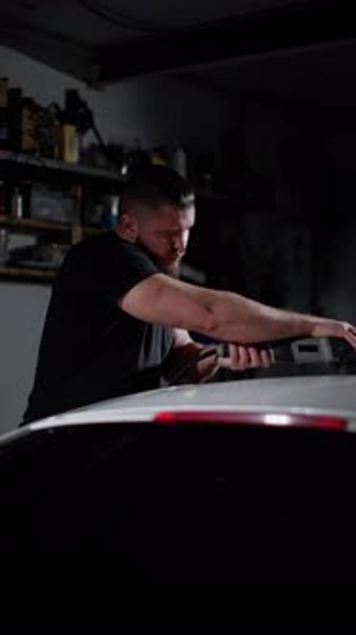 Man Polishing Car in Dark Garage