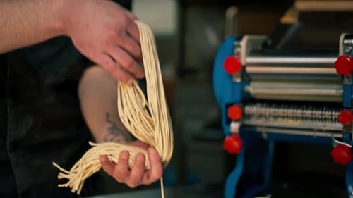 Close Up in Professional Kitchen the Chef Stands Rolling Out the Dough in a Special Machine for