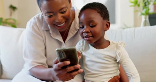 Woman and Child Watching Phone on Couch