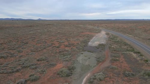 Coche aéreo de seguimiento rápido cruzando la carretera rural del interior de Australia, paisaje árido