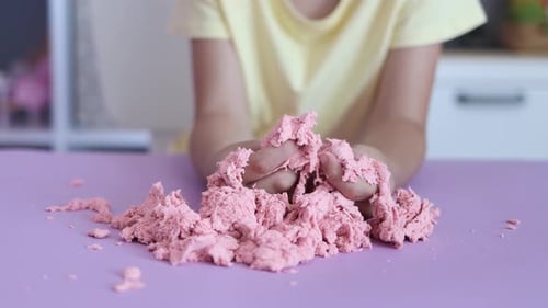 Child Playing with Pink Kinetic Sand at Table