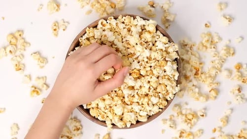 Popcorn Tossed in a Wooden Bowl on a White Background Slow Motion Video Female Hand Takes Popcorn