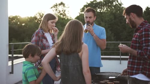 Exciting Family Barbecue in Open Area on Summer Evening Happy Family Eating Snacks Drinking Juice
