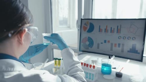 Scientist Inspecting Liquid in Lab with Data Displayed