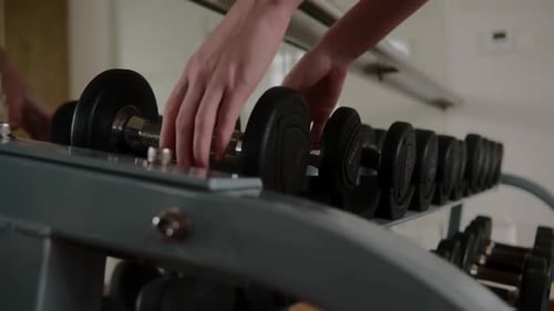 Female Hands Bodybuilding Dumbbells in the Gym Closeup Woman's Hands Taking Weight Lifting in Sport
