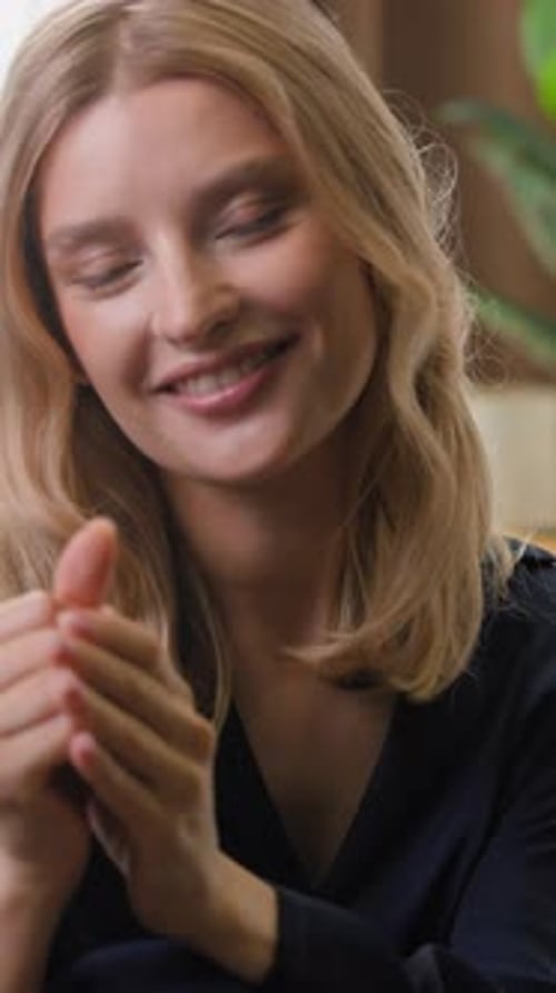 Mujer caucásica feliz mirando a la cámara sonriendo frotándose las manos con crema, aplicando loción de manos suave