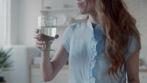 Mujer sonriente bebiendo agua en la cocina