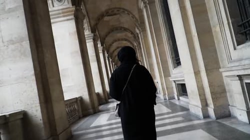 Mulher do sul da Ásia na passarela em arco no pátio interno do Museu do Louvre em Paris, França. Apodrecer