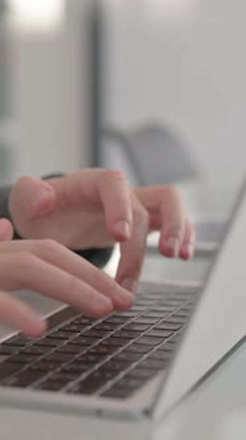 Fingers Typing on Laptop Keyboard in Office