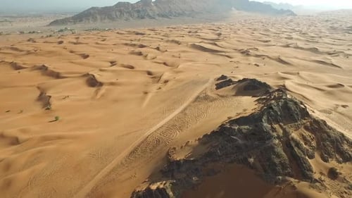 Cinematic 4K Drone Footage of a Rugged Desert Mountain Amidst Dunes