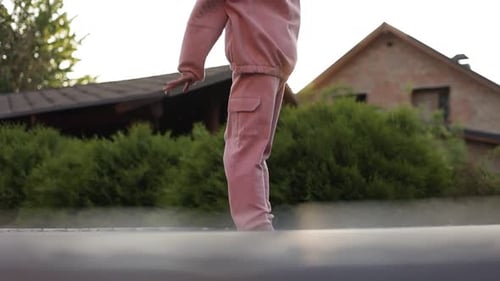 Girl Jumps on a Trampoline in Suburban Yard