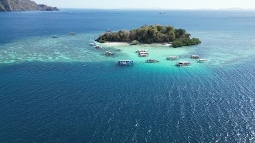 Drone Long Shot of CYC Island in Coron with Tour Boats at Reef on Sunny Day