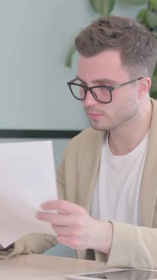 Excited Young Man Reads Good News at Desk