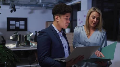 Biracial man and Caucasian woman review business documents in an office