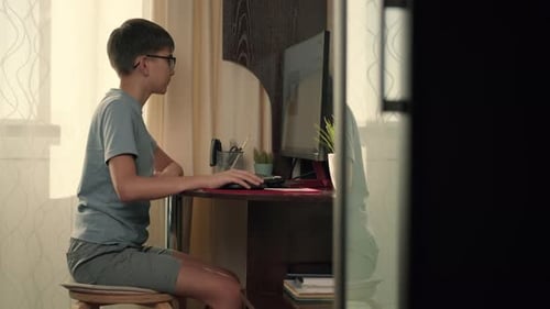 A Boy Solves Interactive Exercises Using a Computer at Home While Sitting at a Table