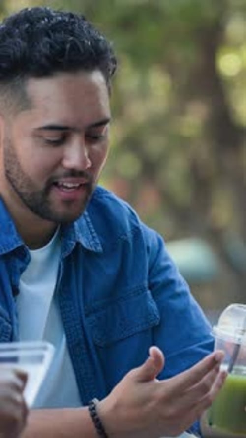 Man sipping green drink outdoors, raising cup and causing health icons to pop around cup reacting