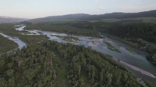 Drone flies over the many arms and streams of the Snake River. Mountains surround the valley at dusk
