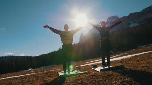 Two Young Women Doing Yoga Outside Mountains and Forest on