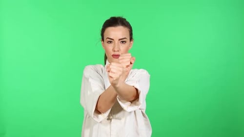 Brunette girl in kung fu wushu uniform practicing wing chun chain punches. Green screen for chroma k