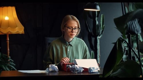 woman in a green shirt sits at a table in her cozy home, typing a novel on a vintage typewriter