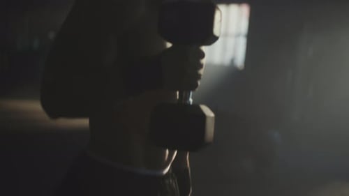 Muscular Man Lifting Weights in Dark Gym
