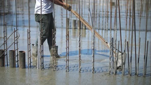 Construction Worker Spreads Concrete on Rebar Site