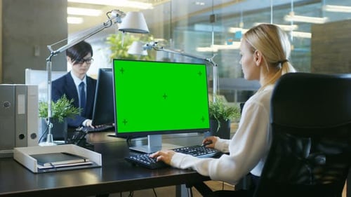 In the Office Businesswoman works at Her Desk on a Personal Computer with Mock-up Green Screen. Col