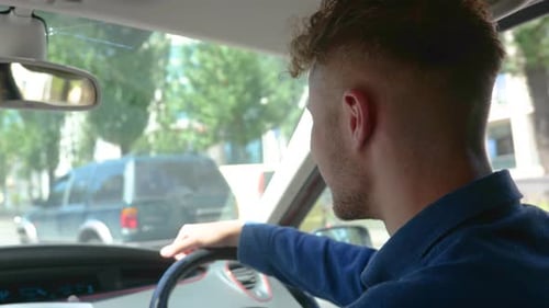Guy Driving Car in the City While Holding Hand on Steering Wheel Looking on Road Right Hand Drive
