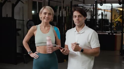 Portrait of Woman and Male Coach Posing during Rehabilitation Training in Gym