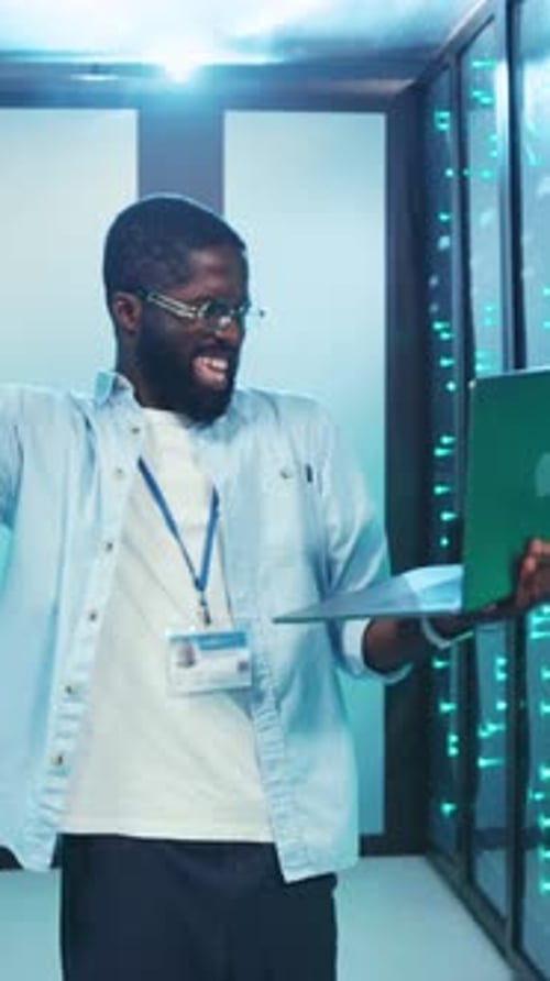 Man Using Laptop in Data Center Smiling