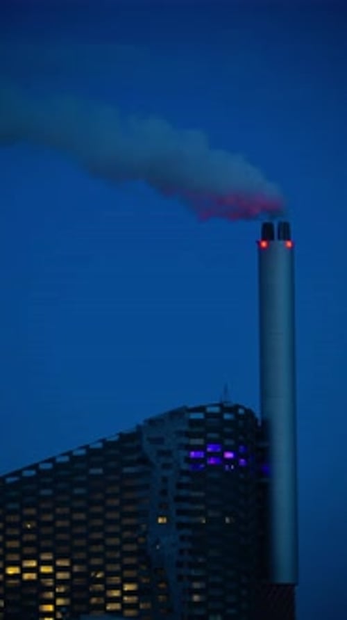 Copenhill waste to energy plant with an architectural facade and illuminated windows at night. Copen