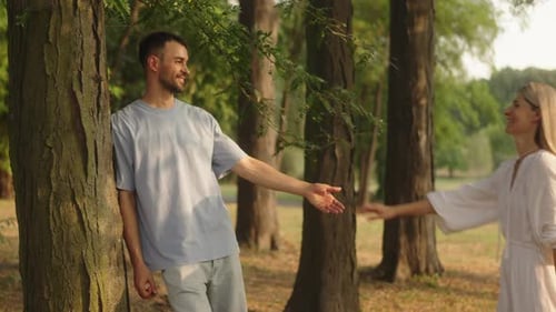 Happy Young Couple Holding Hands in a Park on a Summer Day