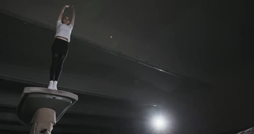 Von unten Junge Sportlerin macht Frontflip vom Tisch beim professionellen Gymnastiktraining in